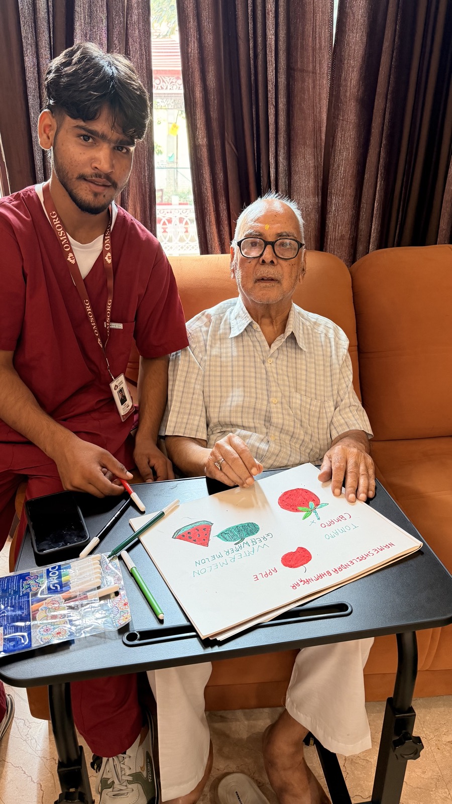 Omsorg caregiver doing a drawing activity with a resident in the lounge