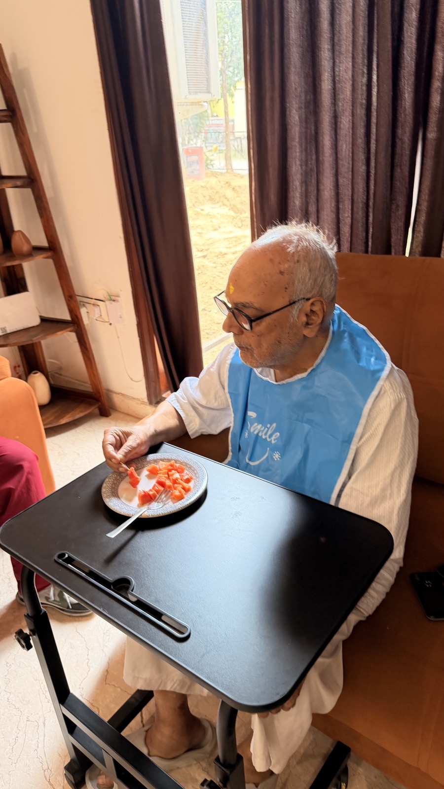 Omsorg resident enjoying a fresh fruit snack at a tray table in the lounge